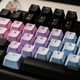 A photo of a dirty mechanical keyboard with pink, purple, and blue keycaps
